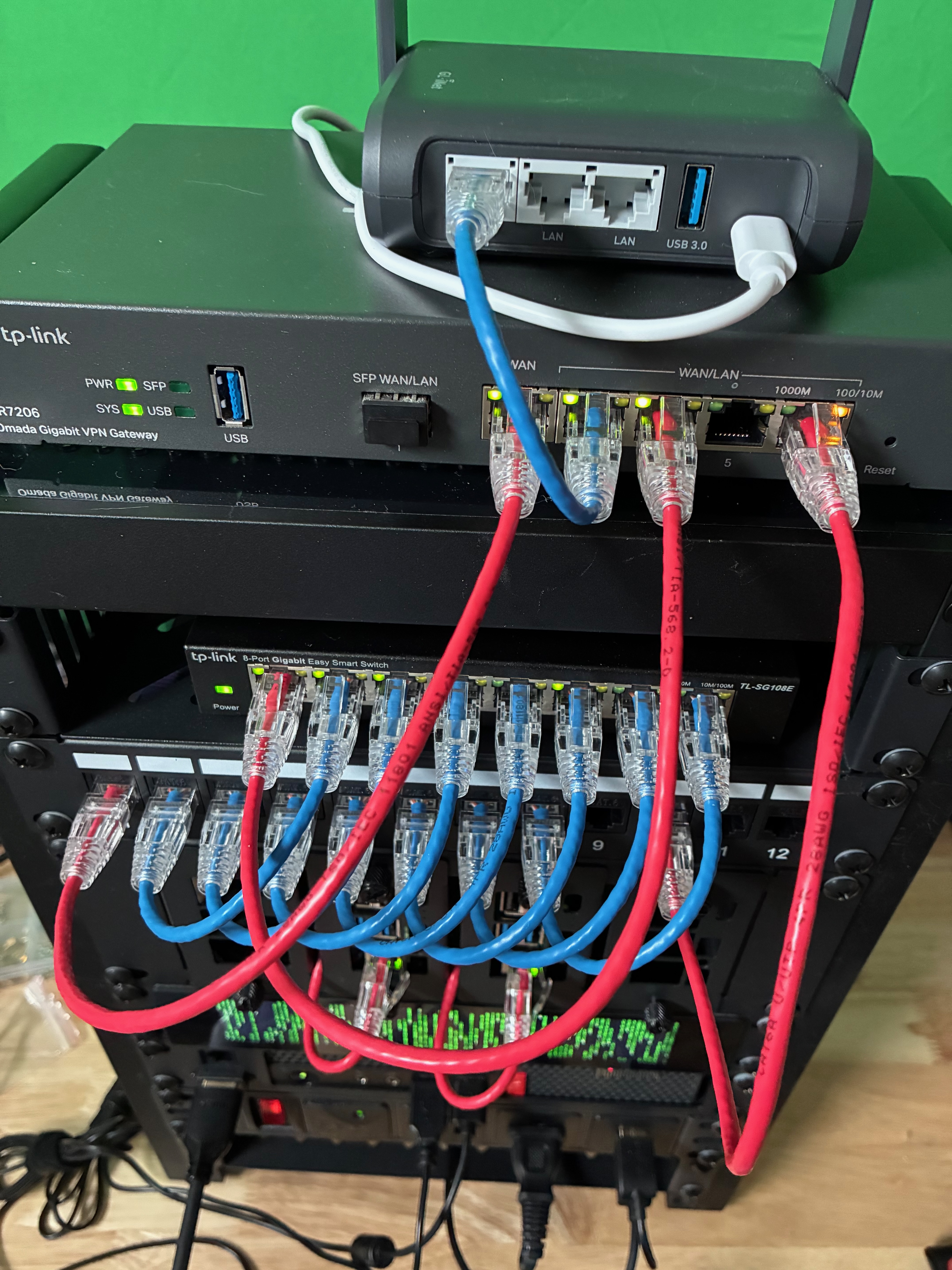 Compact home infrastructure rack with router, switch, patch panel, mini computers, status display, and power distribution